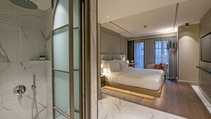 A modern hotel room with a marble bathroom, a large bed, a TV, and a view of the city. - Stayso The House Hotel (Istanbul)