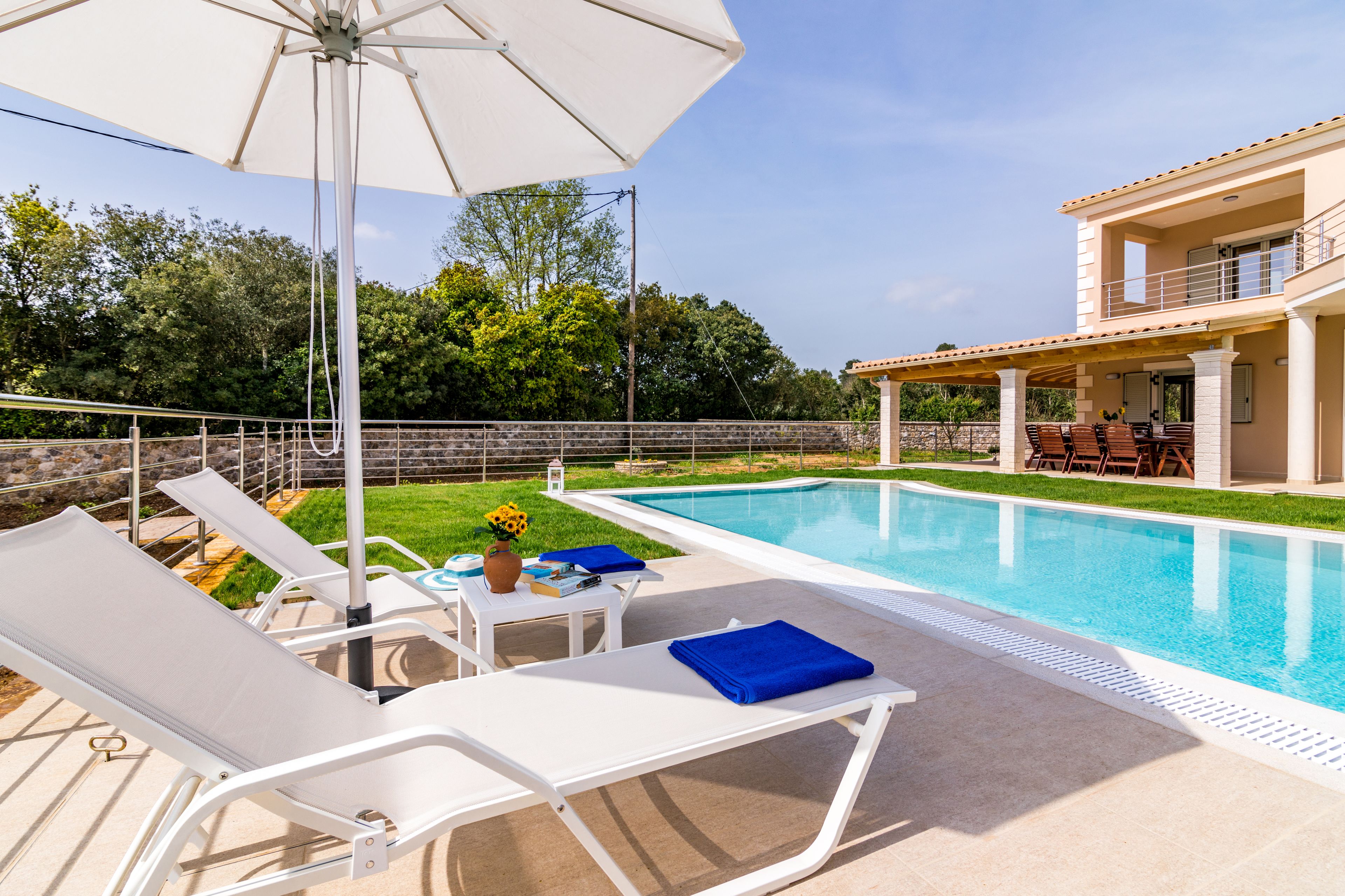 Zona de piscina con sillones de descanso y una sombrilla.