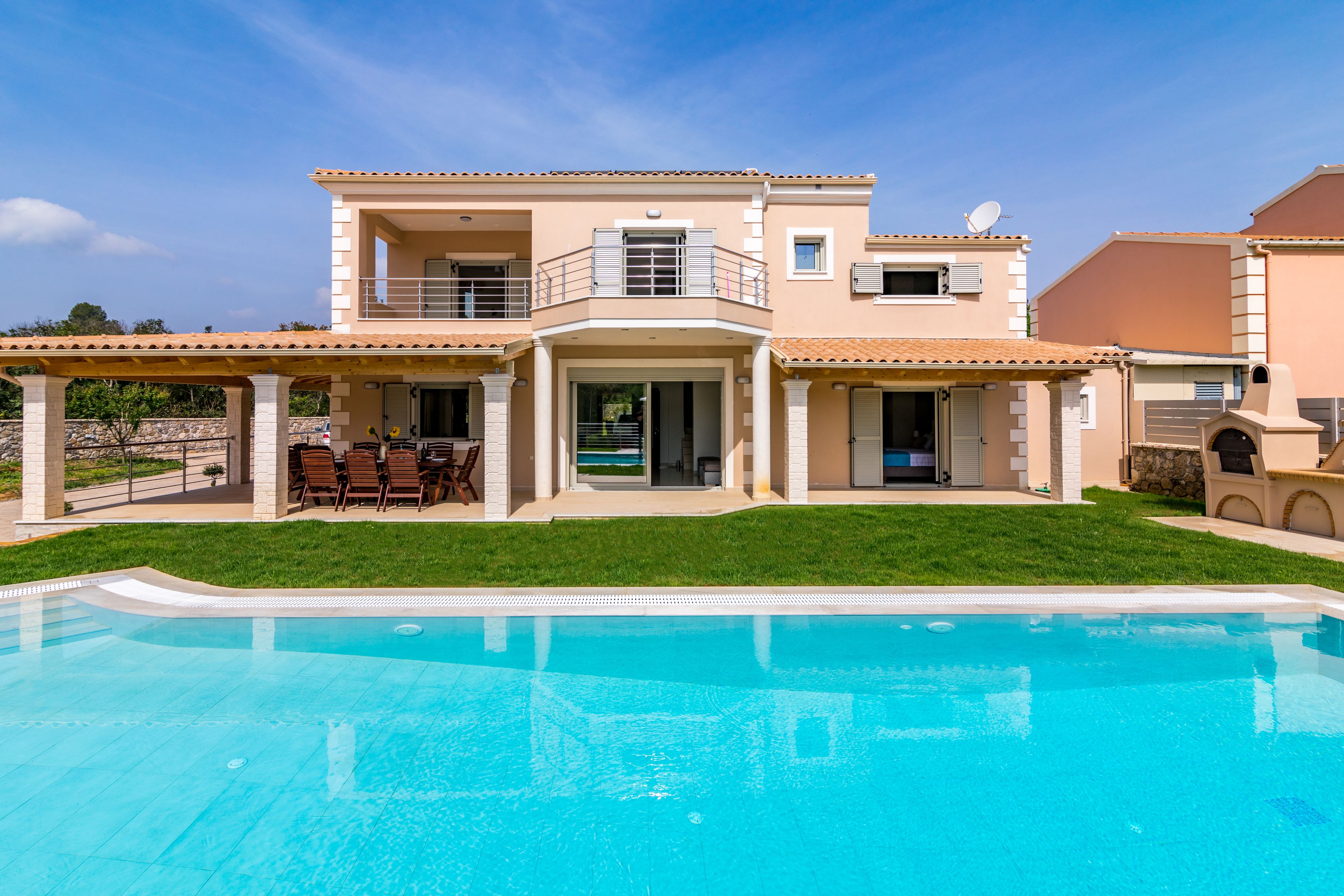 Une maison à deux étages dotée d’une piscine, d’un balcon et d’une terrasse aménagée avec du mobilier d’extérieur.