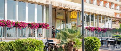 A hotel with a balcony, outdoor seating, and a sign reading 'HOTEL TOURING'.