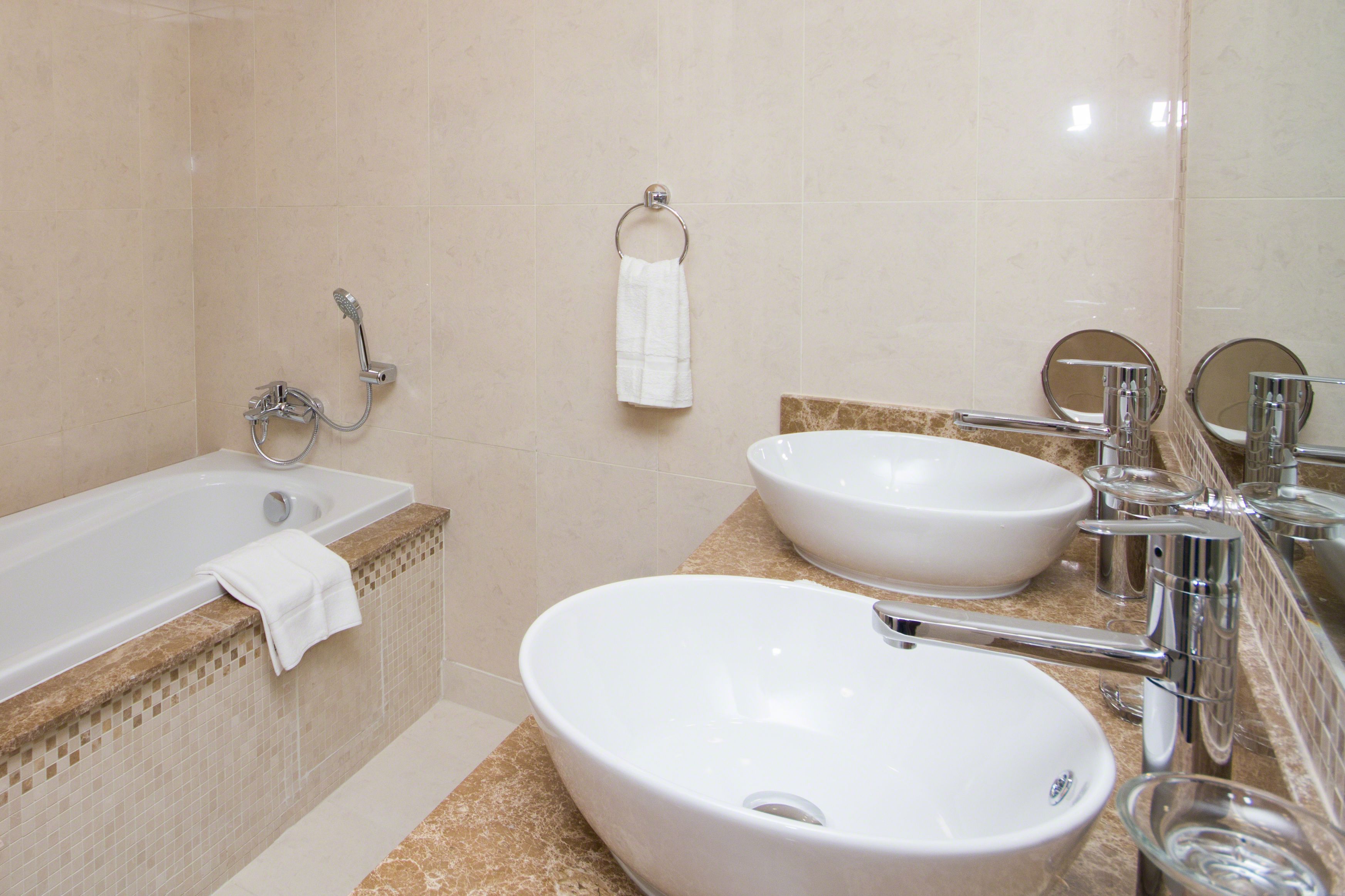 A bathroom with a bathtub, two sinks, a towel rack, and a mirror.