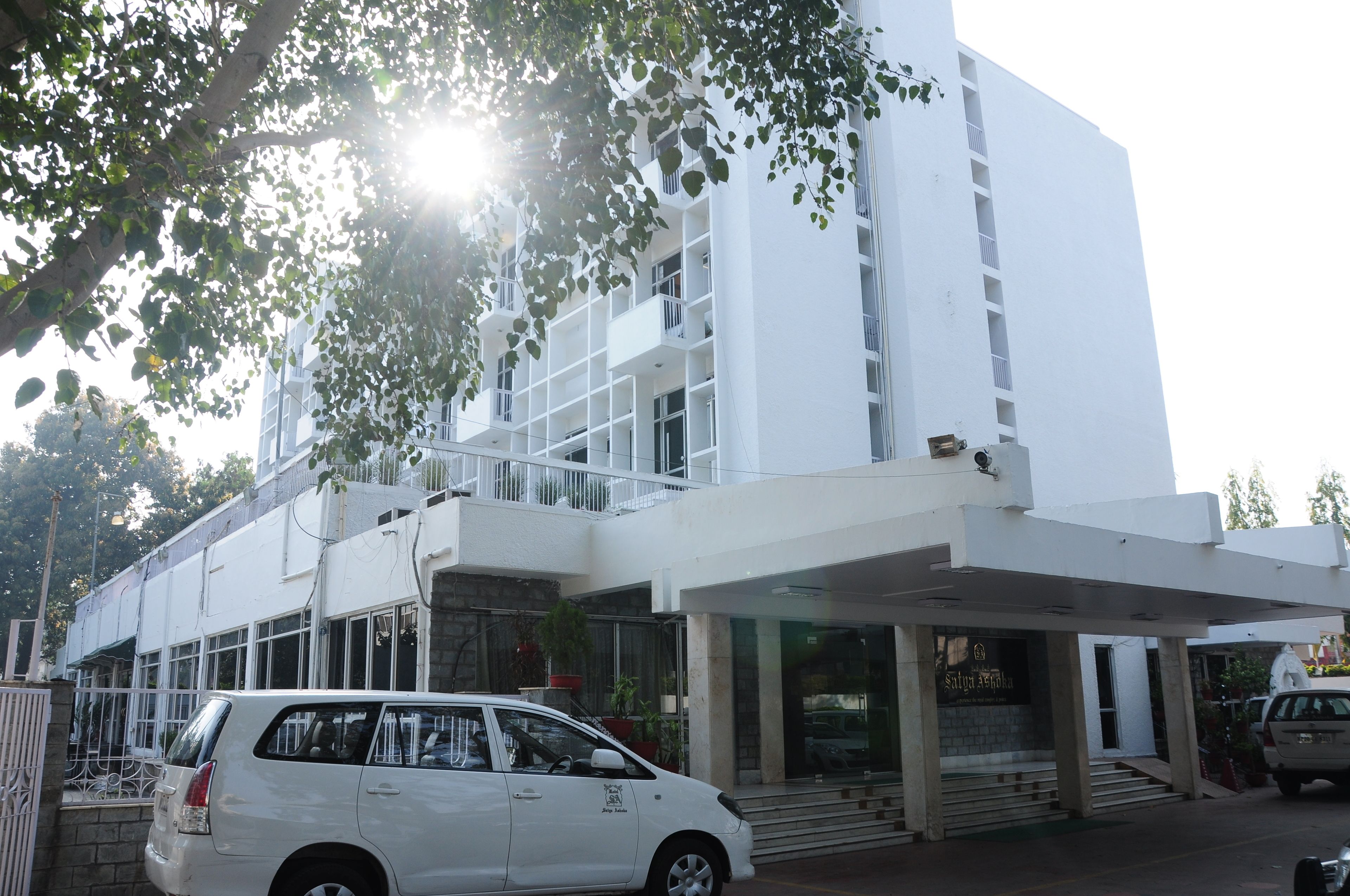 Un edificio moderno con fachada blanca, varios balcones y una zona de entrada cubierta.