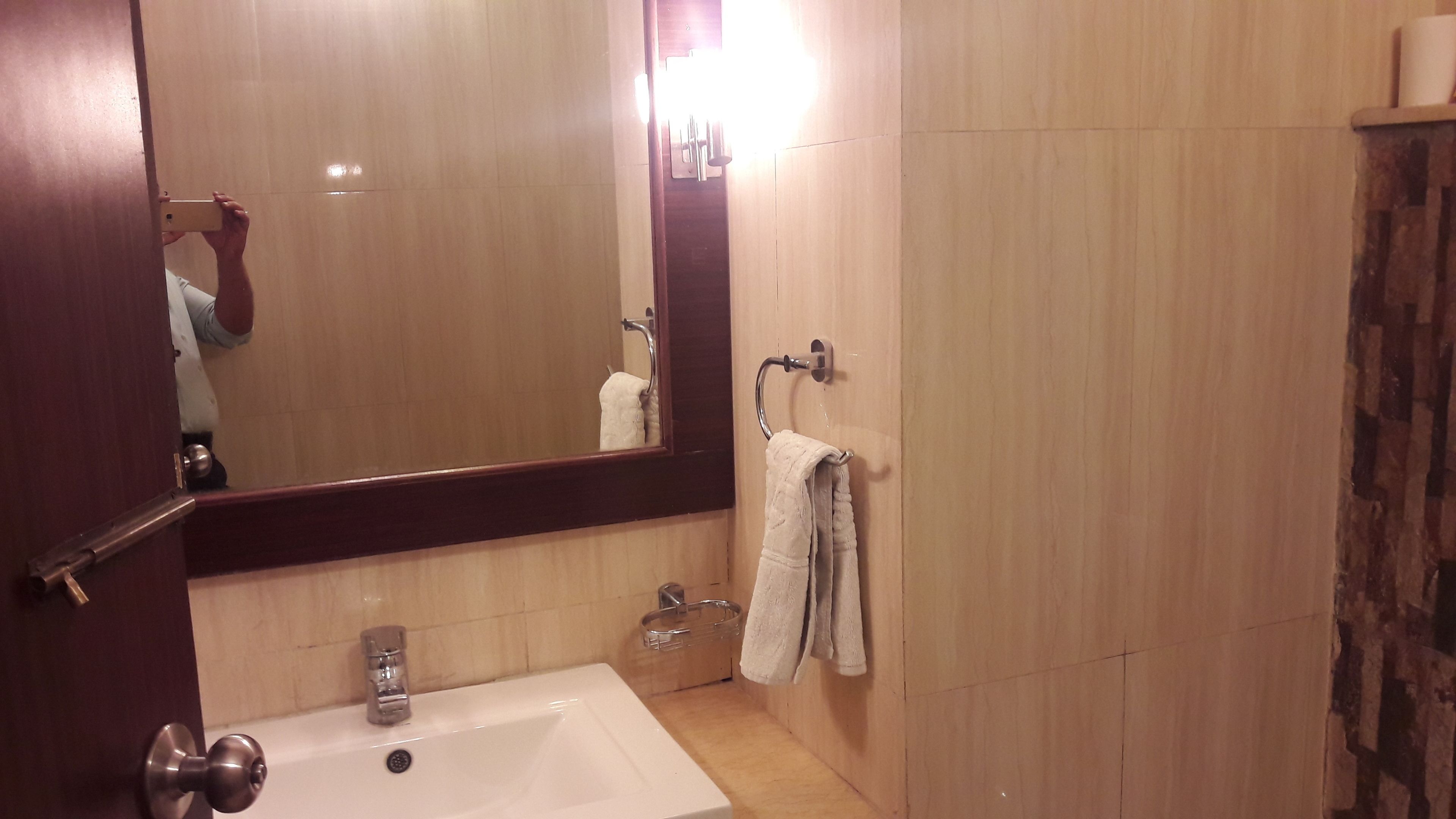 Ein Badezimmer mit Waschbecken, Spiegel, Handtuchhalter und Duschvorhang.
