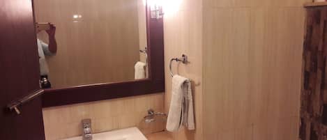 Ein Badezimmer mit Waschbecken, Spiegel, Handtuchhalter und Duschvorhang.