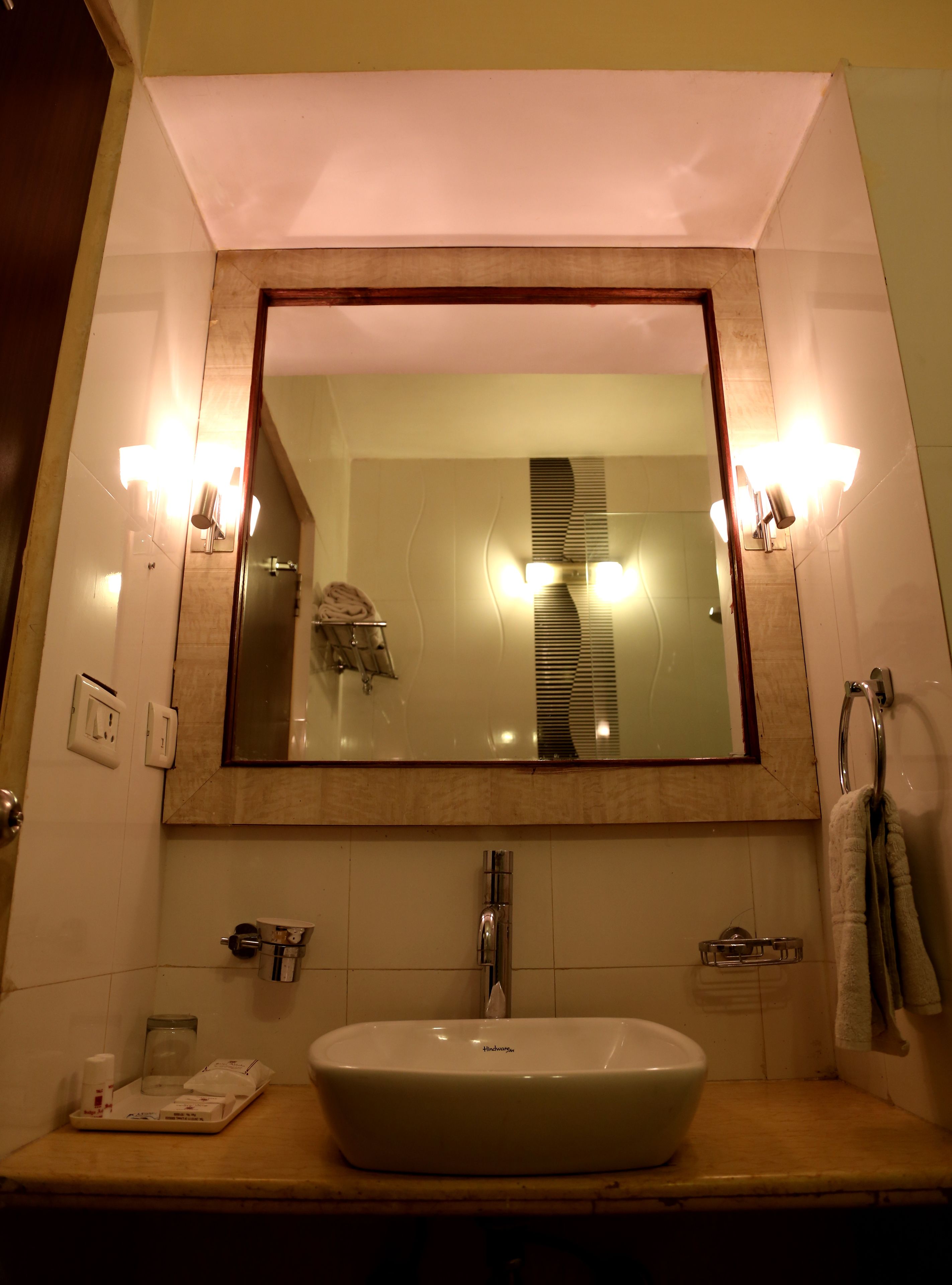 Une salle de bain avec un grand miroir, un lavabo et un porte-serviettes.