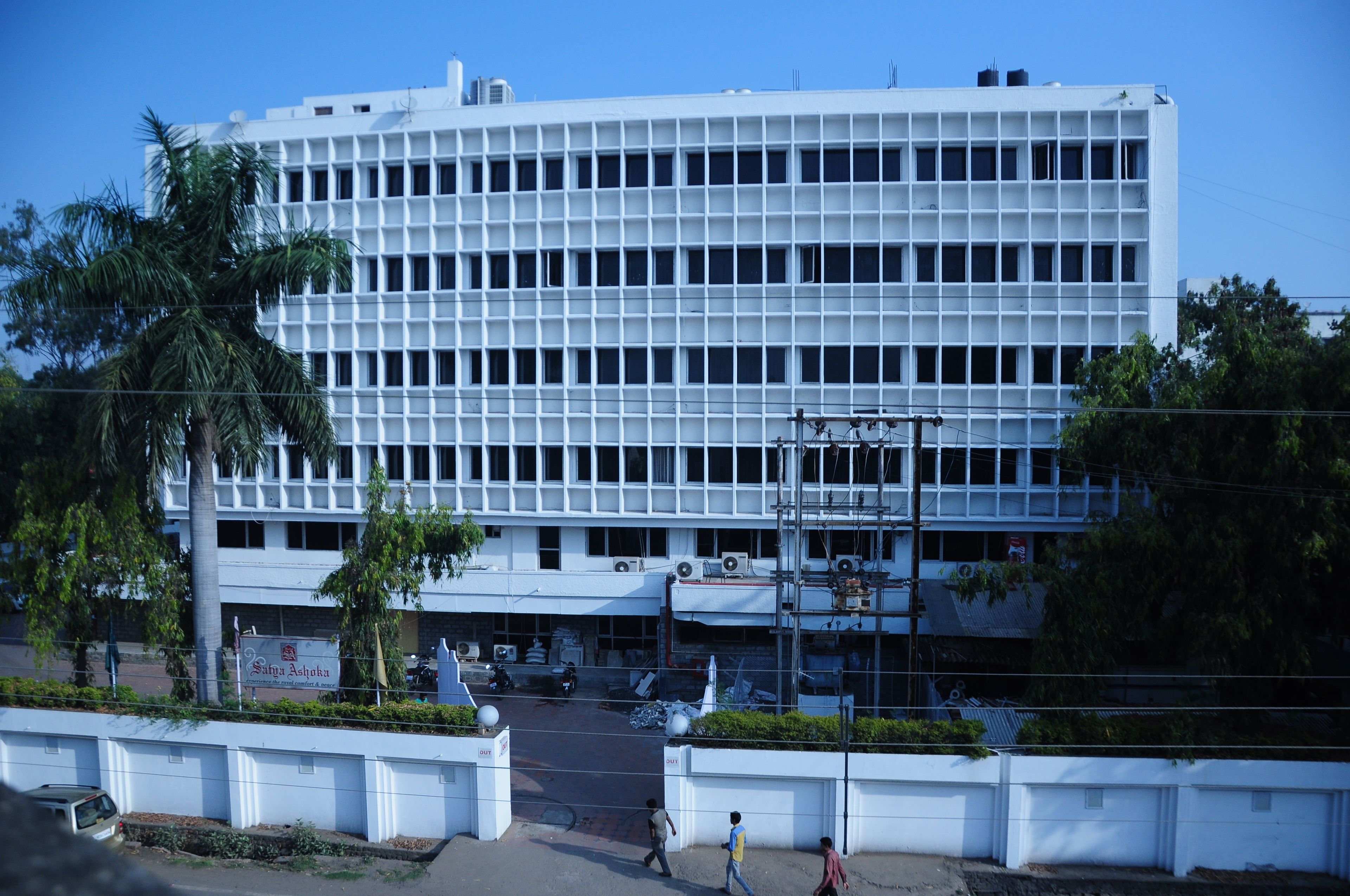 A large, modern building with a grid-like facade, multiple floors, and a flat roof.
