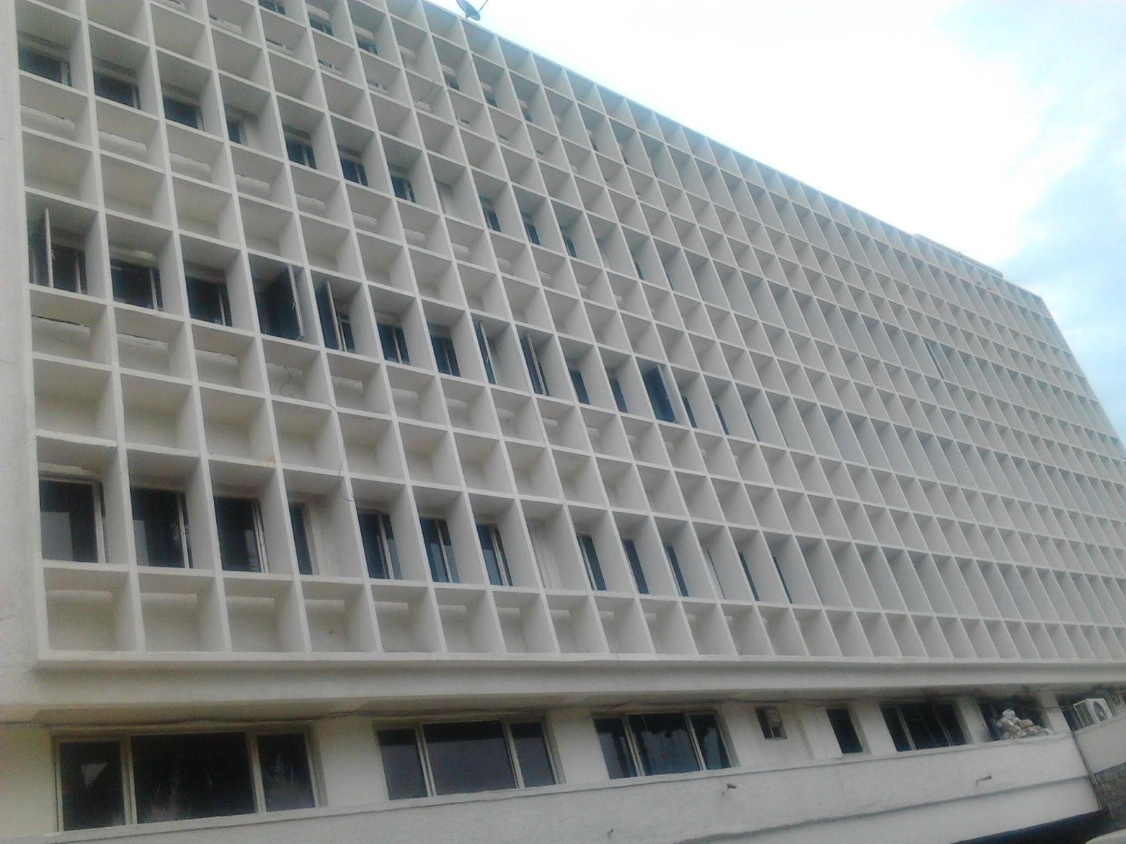 Um edifício moderno com fachada em grade, várias janelas e telhado plano.