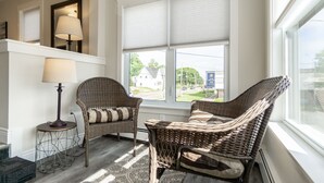 Una habitación acogedora con muebles de mimbre, una alfombra estampada y vistas al exterior.