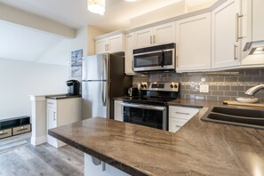 A modern kitchen with white cabinets, stainless steel appliances, and a granite countertop.