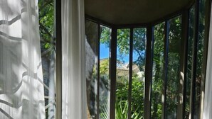 A corner room with a large window, a table with decorative items, and a chair. - Le Complot - Maison Privée à Avignon (Avignon)