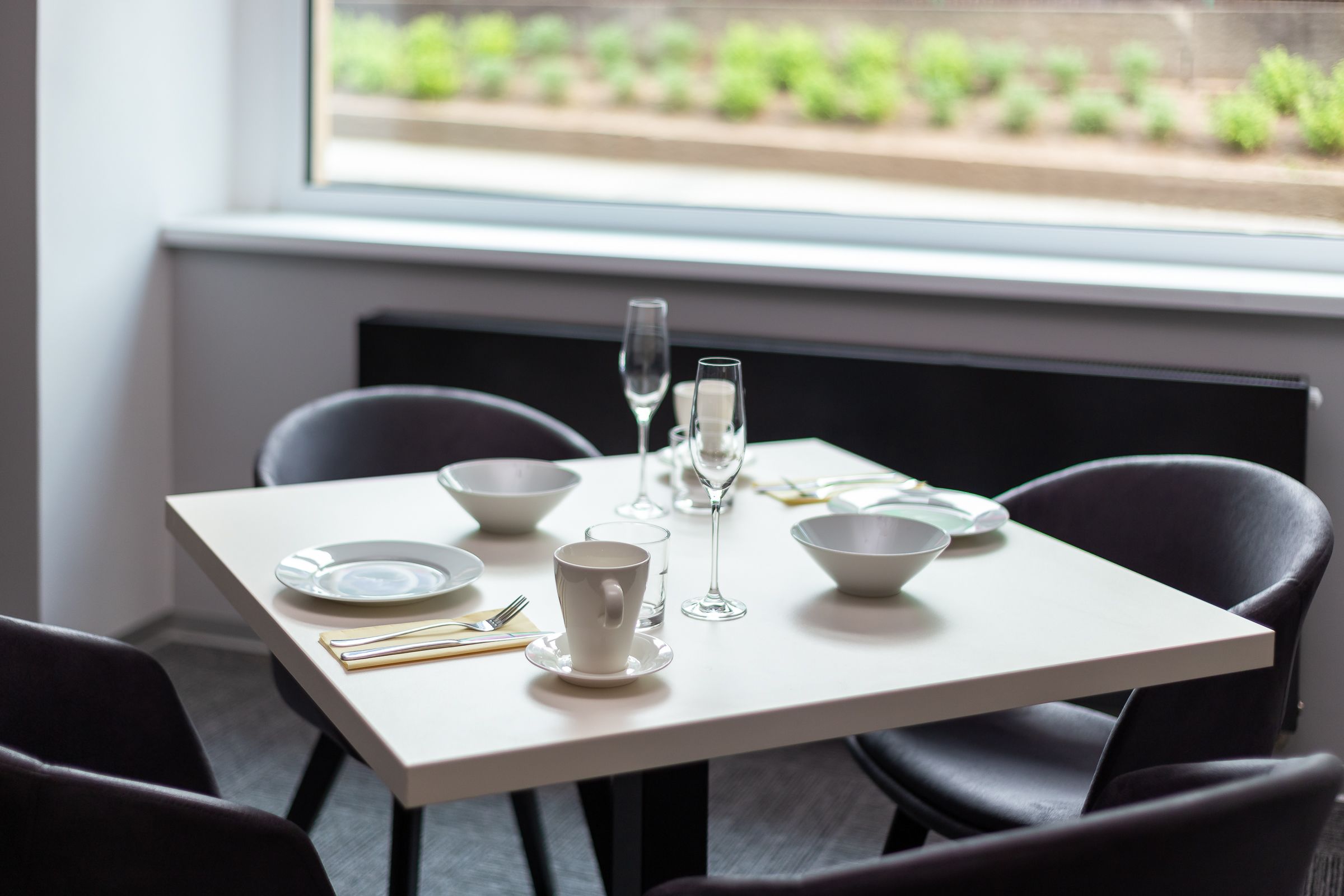 Een eettafel gedekt met borden, kommen, een beker, bestek en wijnglazen.
