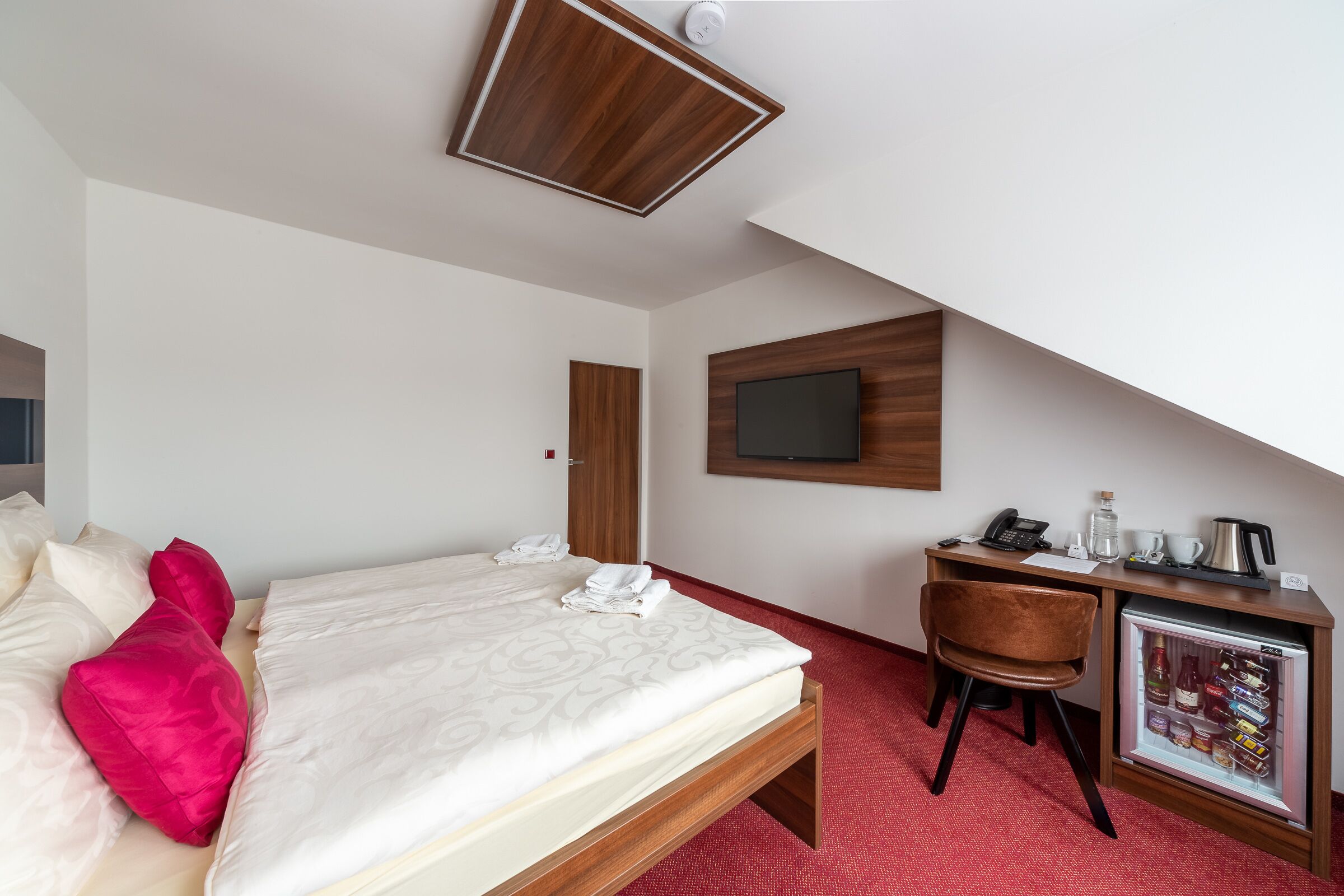 Une chambre d’hôtel équipée d’un lit, d’un bureau, d’une télévision et d’un mini-réfrigérateur.