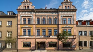 Un edificio histórico con una entrada central, ventanas grandes y detalles arquitectónicos ornamentales.
