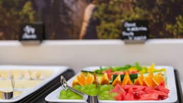 Un bufé con diversas frutas y un cartel que indica la ubicación.