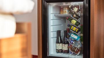 A mini-fridge with shelves containing various food items and bottles.