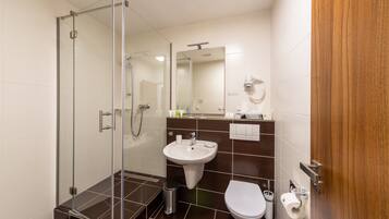 A modern bathroom with a glass shower enclosure, a sink, a toilet, and a mirror.