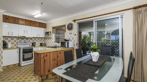 Une cuisine de taille réduite avec des meubles blancs, un îlot central en bois, un four à micro-ondes et une horloge murale.