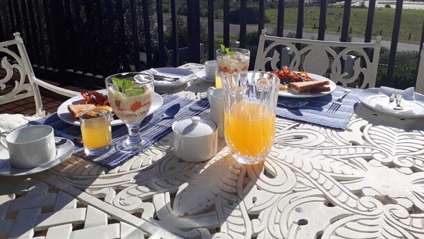 Una mesa lista para el desayuno, con una vista panorámica de montañas y agua al fondo.