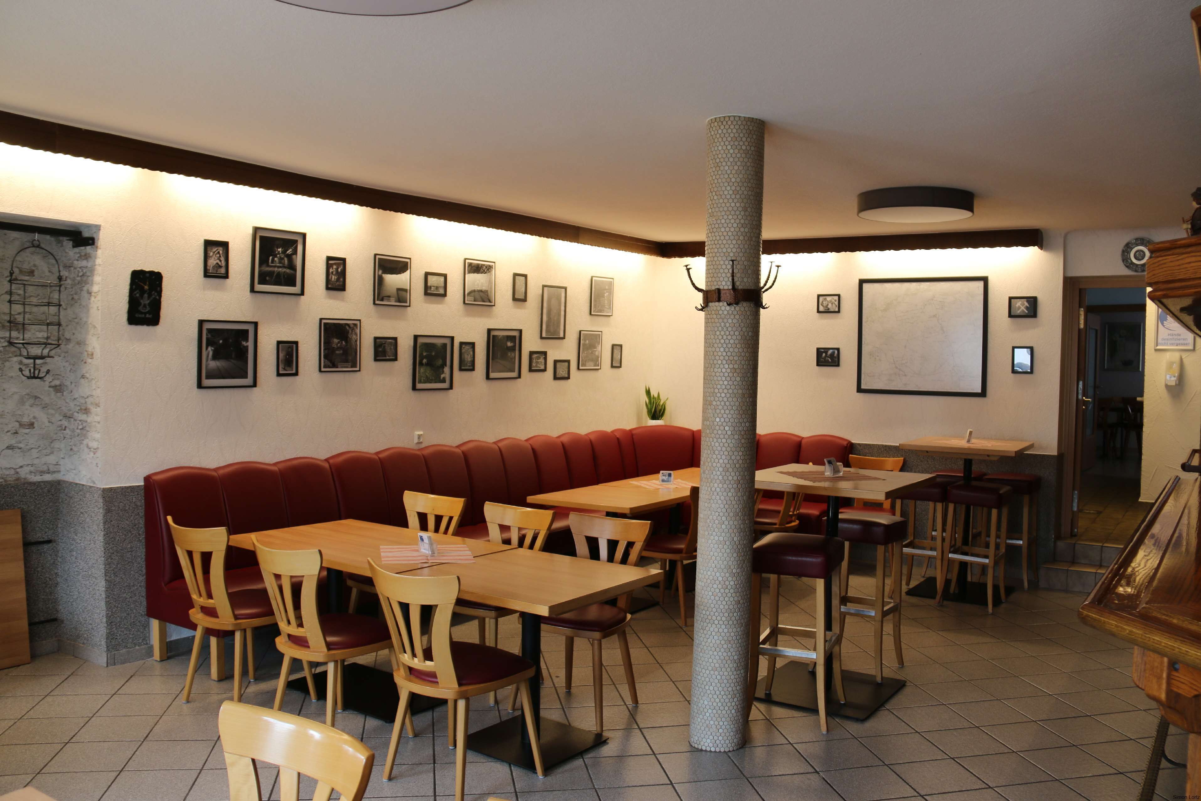 Un restaurante con cabinas, mesas y sillas. Hay cuadros enmarcados en las paredes.