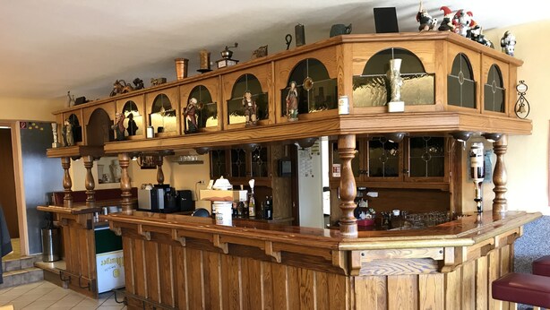 Una barra de madera con varios estantes y espejos, equipada con diferentes utensilios de bar y botellas.