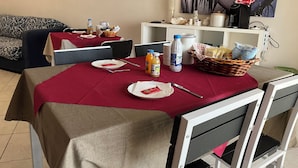 Un espace repas avec des tables dressées pour deux personnes, agrémenté de nappes rouges, d’assiettes, de couverts et de boissons.