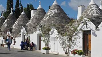 A row of white buildings with conical roofs, some with visible logos, and a pedestrian walking by.
