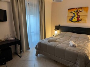 Una habitación de hotel con una cama, un escritorio, una lámpara y un cuadro en la pared.