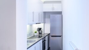 A modern kitchen with white cabinets, stainless steel appliances, and a coffee maker on the counter.