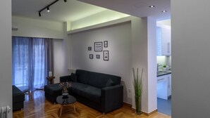 A modern living room with a dark sofa, a small coffee table, and a potted plant.