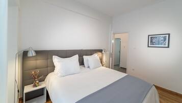 A modern hotel room with a large bed, a bedside table with a lamp, and a framed picture on the wall.