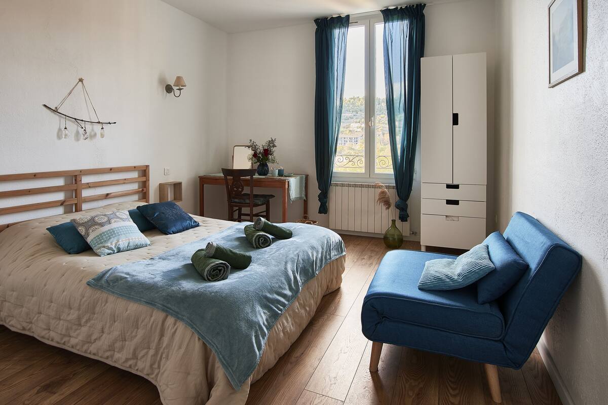 A bedroom with a bed, a chair, a desk, and a wardrobe.