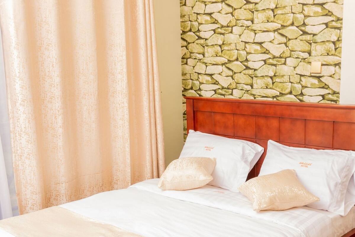A bed with a wooden headboard, white bedding, and two pillows.