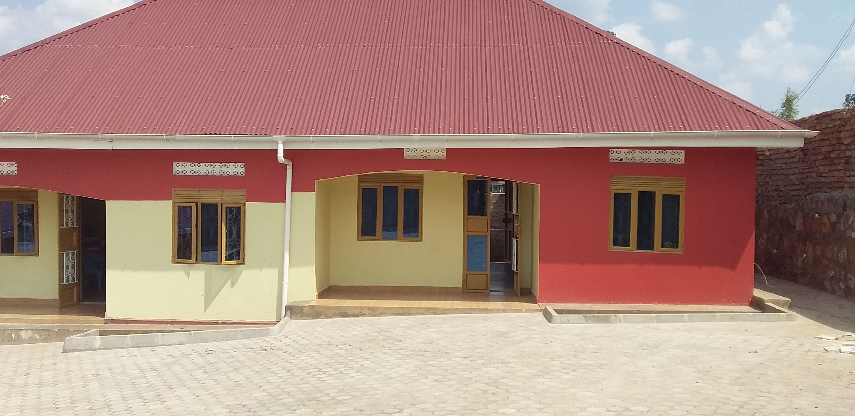 A building with a red roof and a yellow facade, featuring two doors and windows with yellow frames.
