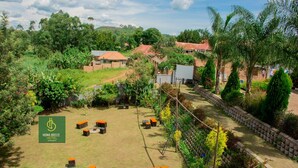 A hotel with a grassy lawn, outdoor seating, and a view of surrounding greenery and buildings. - Hoima Breeze Hotel (Hoima)