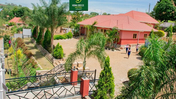 A hotel with a red roof, surrounded by greenery and a paved courtyard. - Hoima Breeze Hotel (Hoima)