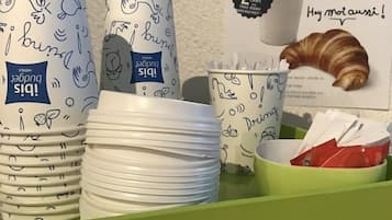 A breakfast tray with plates, cups, and a croissant.