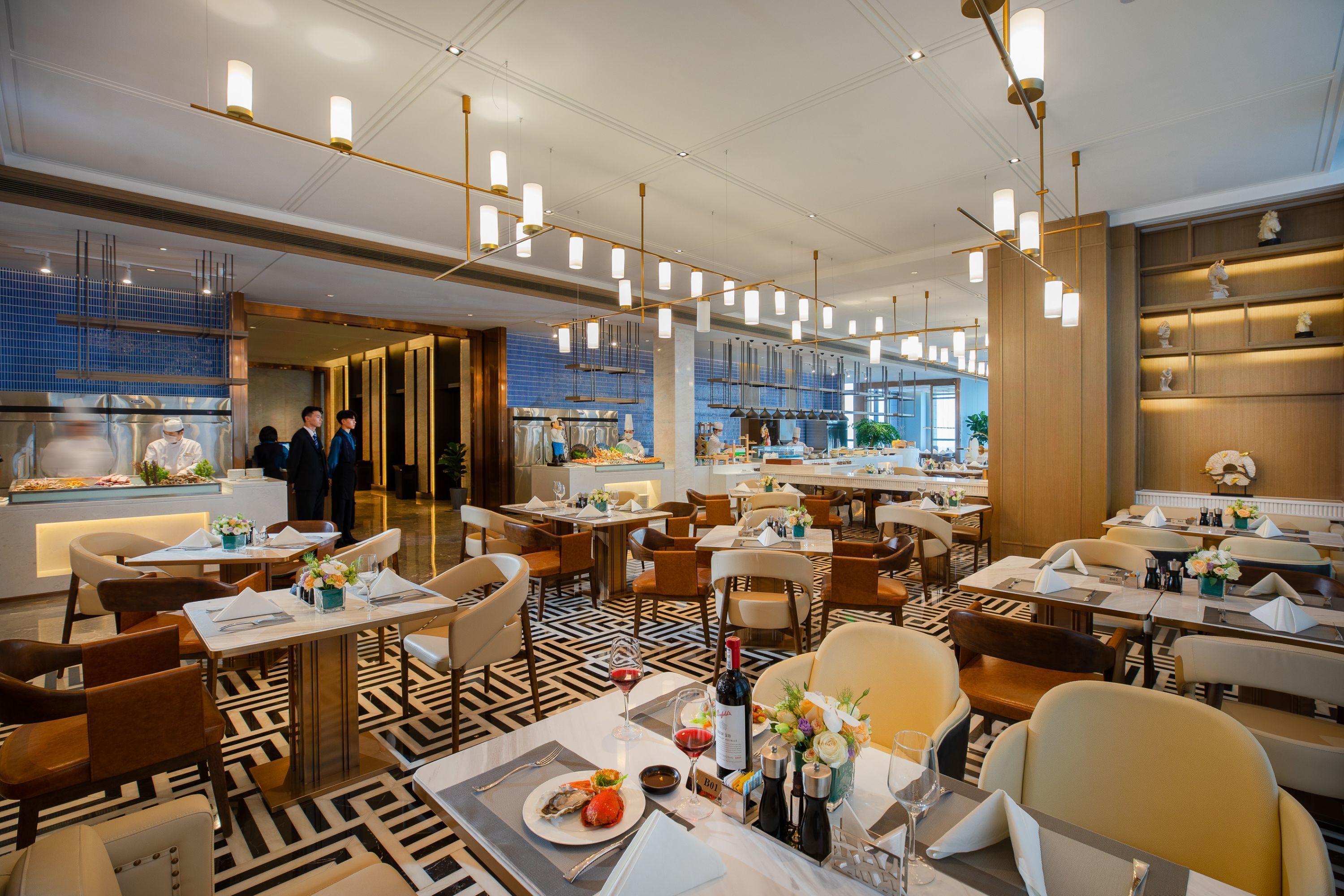 A spacious restaurant with multiple dining tables, modern lighting fixtures, and a patterned floor.