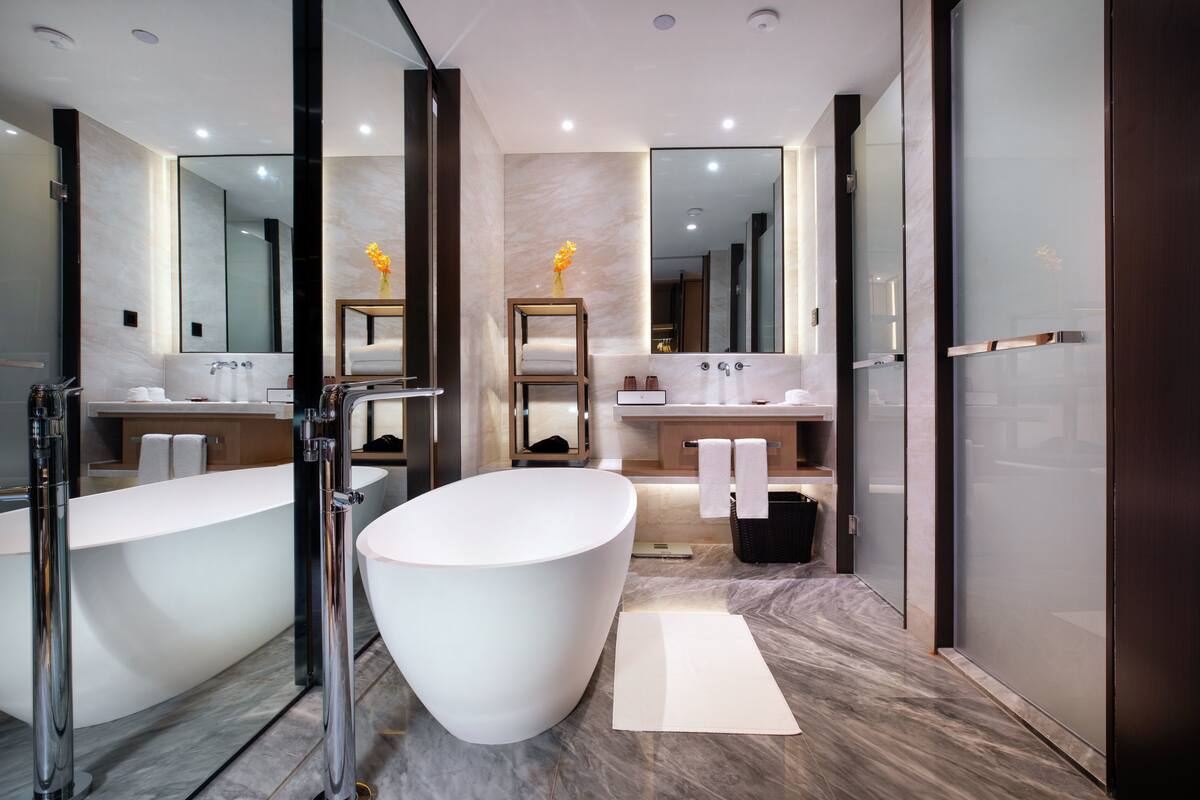 Un baño moderno con una bañera independiente, un espejo grande y un mueble de tocador con lavamanos.