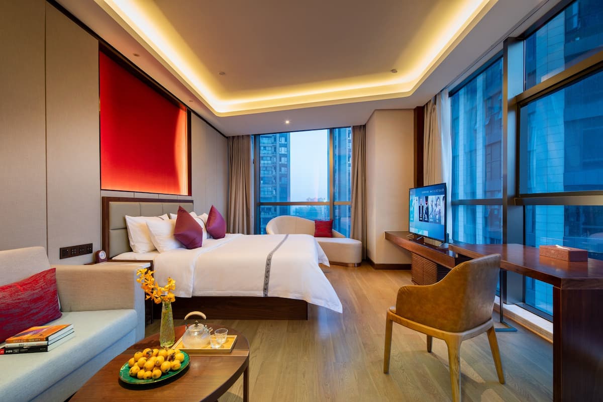 Una habitación de hotel moderna con una cama grande, un sofá, un escritorio y un televisor.