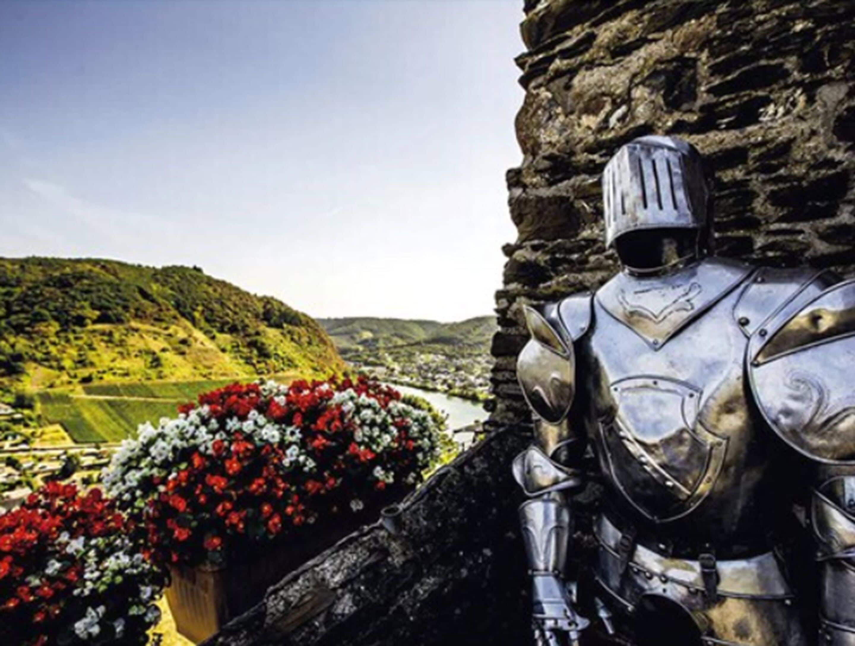 A knight statue next to a stone wall with a flower arrangement.