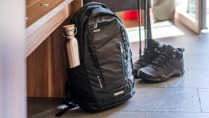 Una habitación con un escritorio de madera, una mochila negra y un par de zapatos.