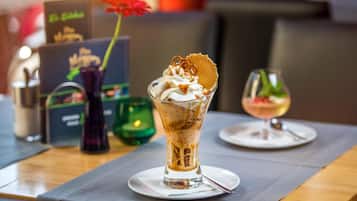 Postre con crema batida y una galleta sobre un vaso, una vela y un menú en una mesa.