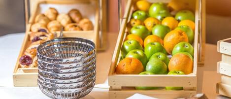 A table with wooden crates containing fruits and pastries, and a glass bowl.