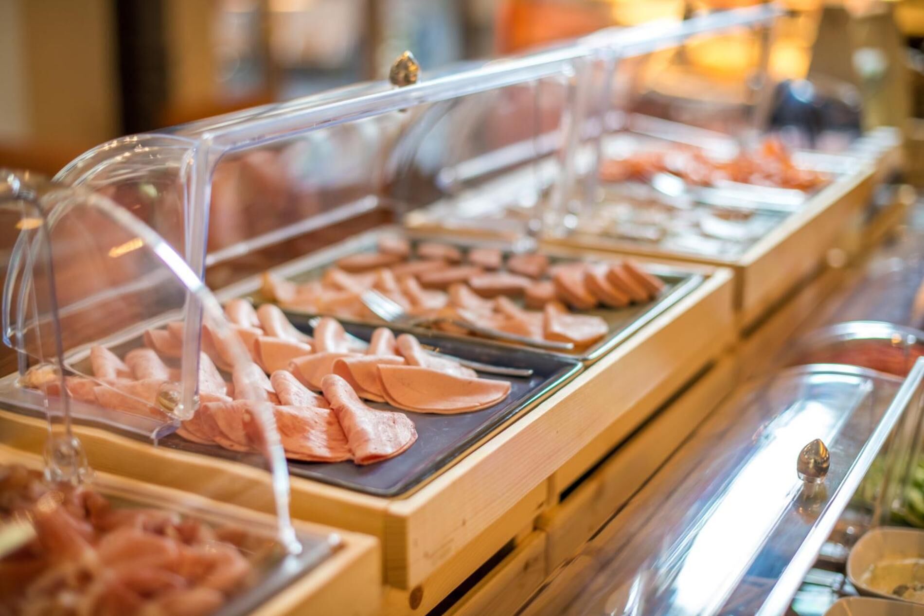 Un bufé con diversos alimentos presentados en recipientes de plástico transparente.