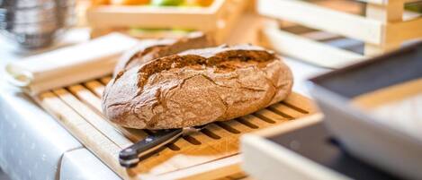 A loaf of bread on a wooden cutting board with a knife beside it, placed on a table with a white tablecloth.