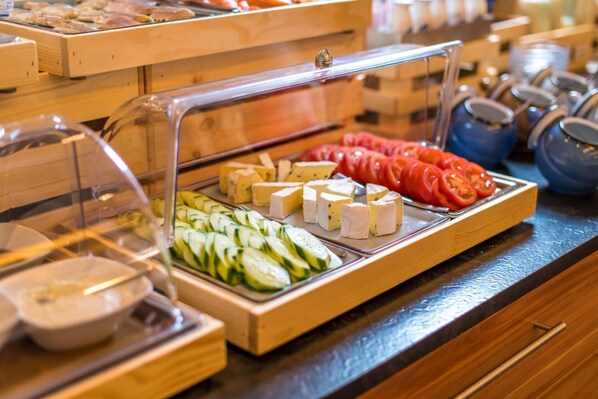 A buffet with various cheeses, sliced cucumbers, and tomatoes. - Hotel Cochemer Jung (Cochem)