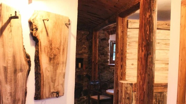 A rustic interior with exposed wooden beams, a stone wall, and a wooden door. - Tiefala's Eck (Stubenberg)
