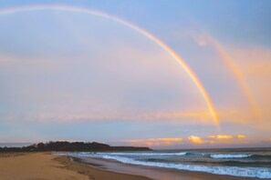 A beach with a rainbow and ocean waves.