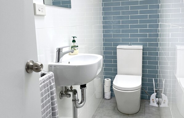 A bathroom with a white sink, a toilet, and blue-tiled walls.