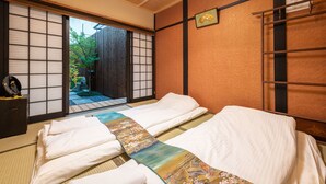 A traditional Japanese-style room with tatami flooring, a futon bed, sliding doors, and a small washbasin. - KumoMachiya Takoyakushi (Kyoto)